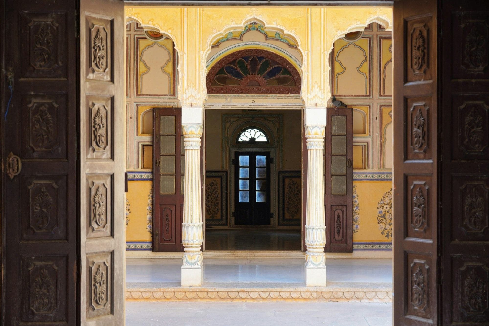 Carved doors opening onto a sunlit courtyard